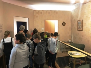 Die Lehrerin erklärt den Schülern die Ausstellung des Stadtmuseums, Schüler schauen sich gespannt Ausstellungsstücke an