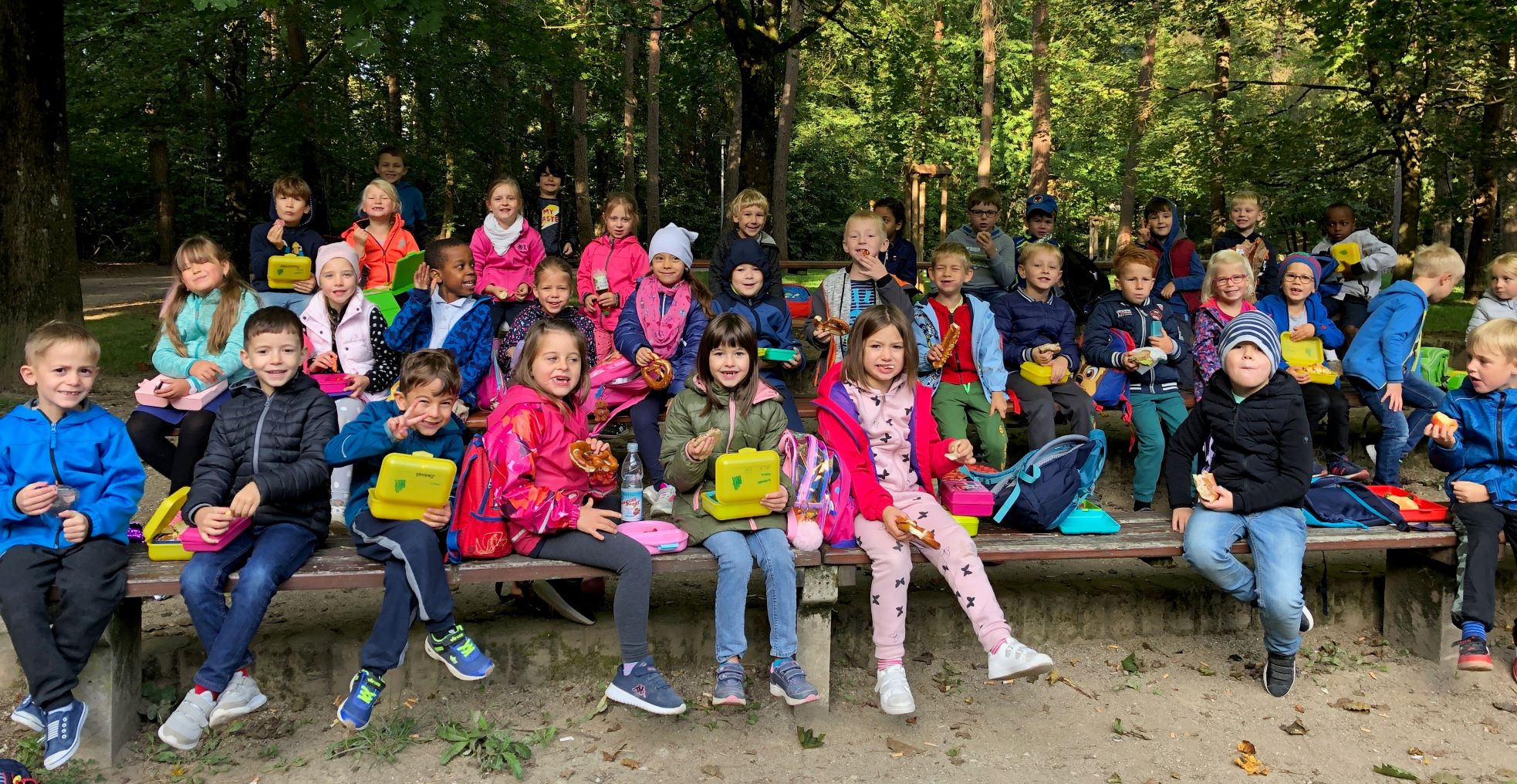 Brotzeitpause auf den Bänken im Stadtpark am Wandertag 1. Klassen