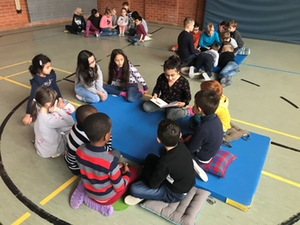 Kinder lauschen am Vorlesetag gespannt einer Geschichte in der Turnhalle